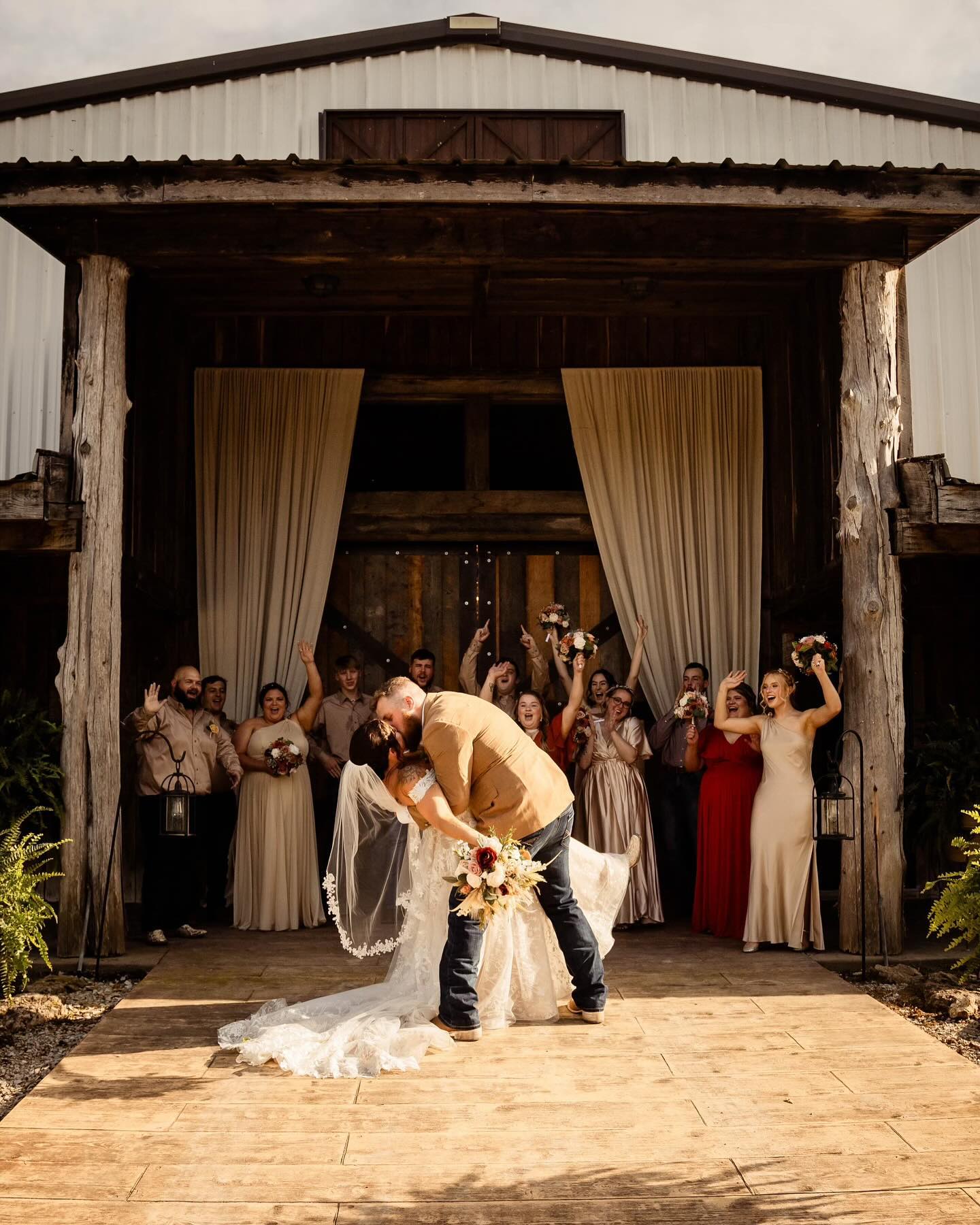 452892108_1019165490216051_4694248235848779633_n bride and groom kissing while wedding party cheers