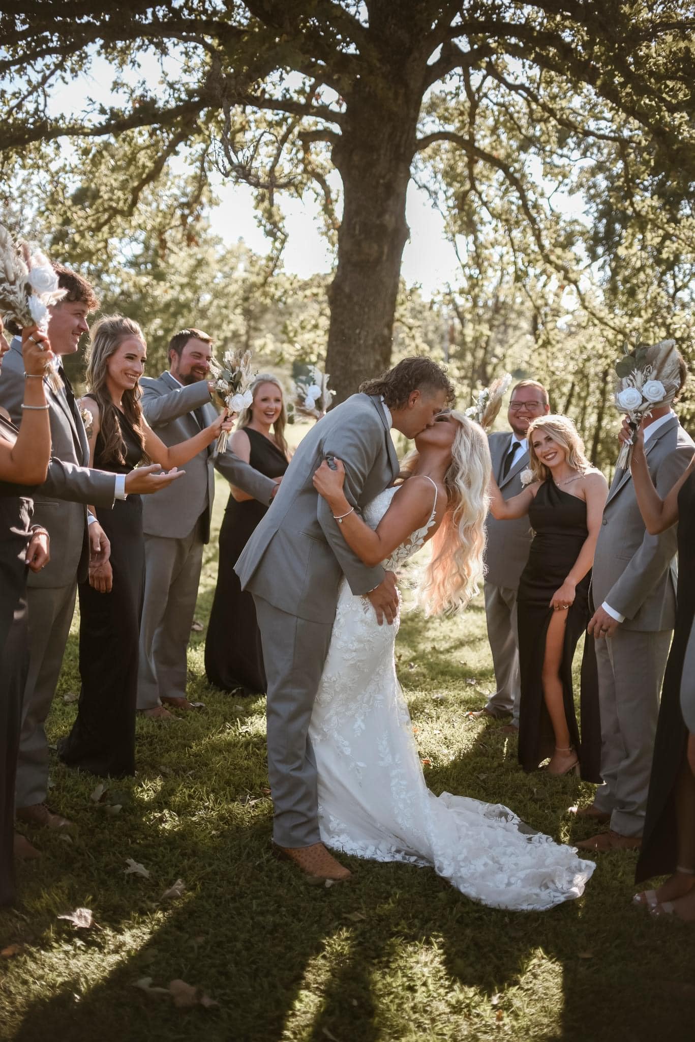 456247943_1036667285132538_6923387970599760836_n bride and groom kissing surrounded by wedding party