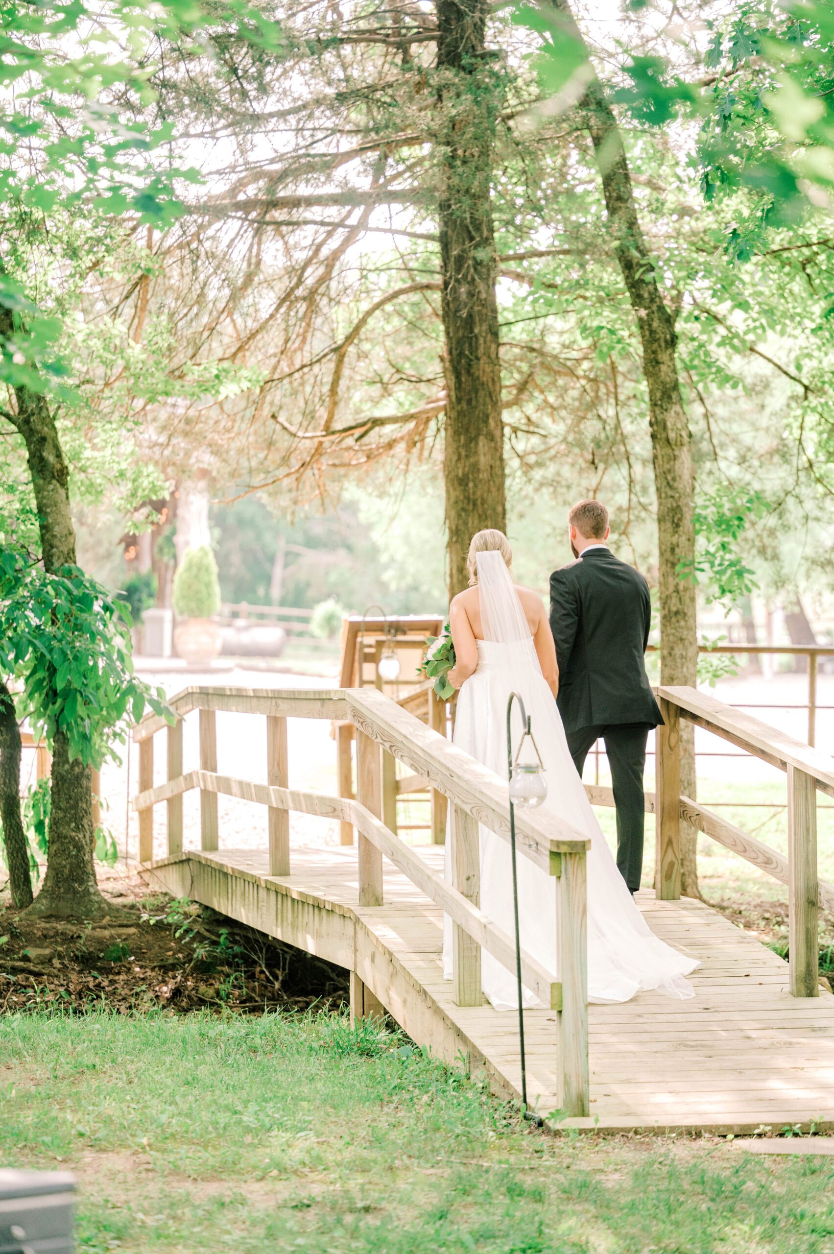 bride and groom walking across wooden bridge at wedding venue